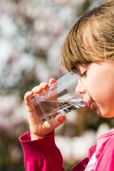 女の子はガラスから水を飲む — ストック写真