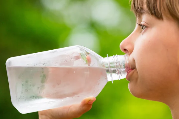 Child drinking clean tap water from transparent plastic bottle — Stock Photo, Image