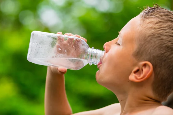 Jonge jongen drinkwater uit de fles — Stockfoto