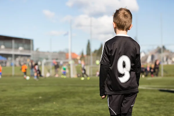 Niño viendo partido de fútbol juvenil — Foto de Stock