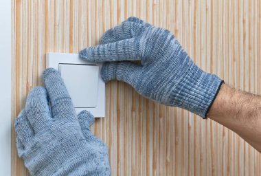 Odaya bir elektrikçi tarafından duvar anahtarı yerleştirilip, yakın çekim koruyucu eldivenler takılacak.