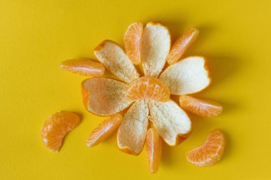 Sarı arka planda soyulmuş mandalina ya da mandalina meyvesi, düz.