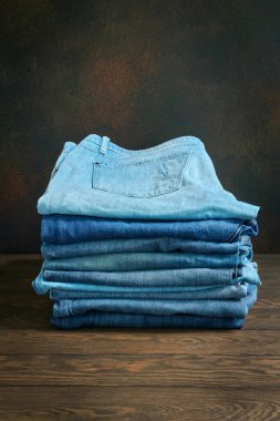 Taklit alanı olan ahşap bir masada süslü kot pantolon yığını.