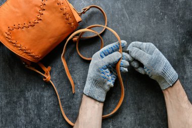 Deri giyen profesyonel, kadın çantasının deri kayışında bir delik açıyor. Üst manzara, meslekler.