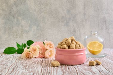 Seramik bir kasede esmer şeker, güller ve limon ahşap bir masada, hayat