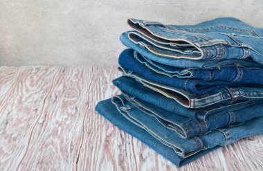 Ahşap masada katlanmış kot pantolon, metin için yeri olan gri arkaplan