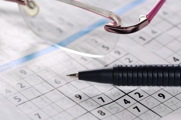 Pencil and glasses lying on a newspaper with a sudoku puzzle — Stock Photo, Image