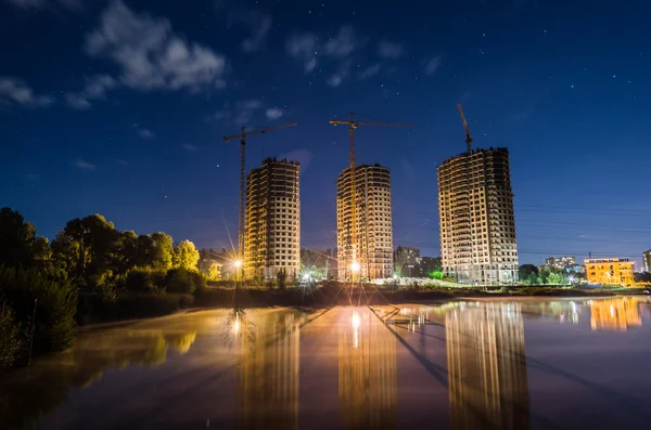 Construcción nocturna con luces contra el cielo azul — Foto de Stock