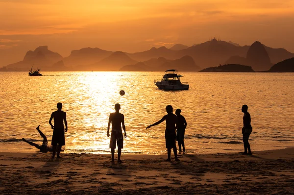 Silhouetten von Menschen, die am Strand Fußball spielen — Stockfoto
