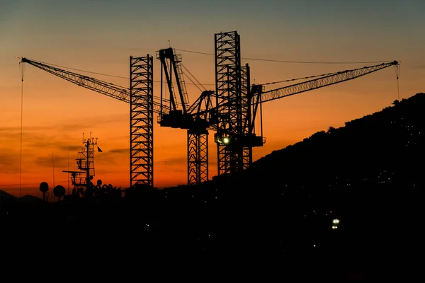 Silhouette of Industrial Cranes of Sunset