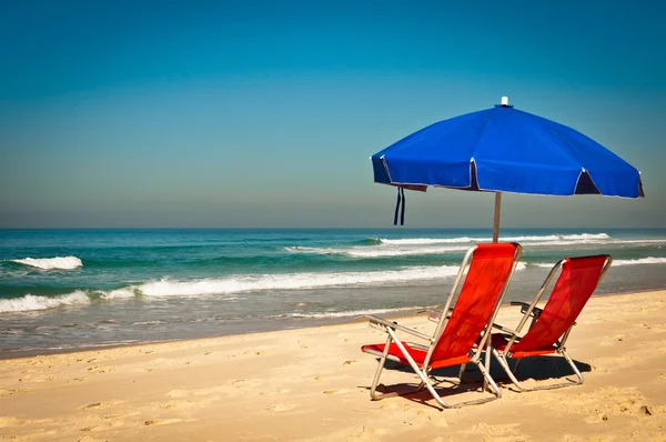 Liegestühle und Sonnenschirm auf Sand am Strand — Stockfoto