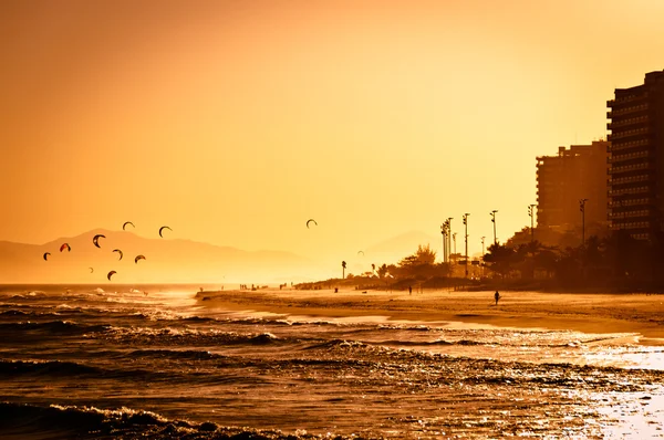 Pôr do sol na praia com montanhas no horizonte — Fotografia de Stock