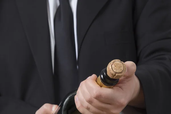 Man in siut opening Champagne bottle — Stock Photo, Image