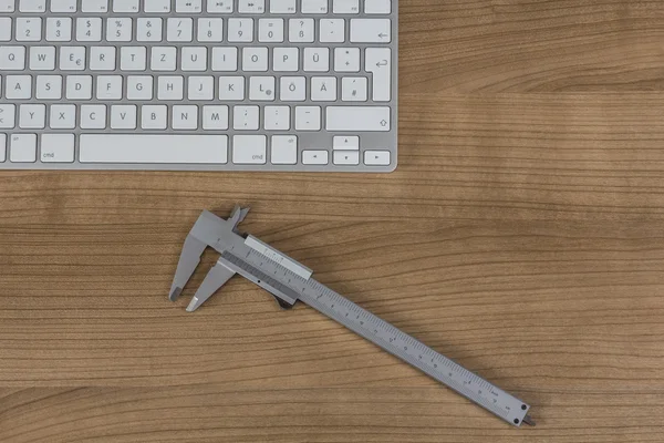 Keyboard and a sliding caliper on Desktop — Stock Photo, Image