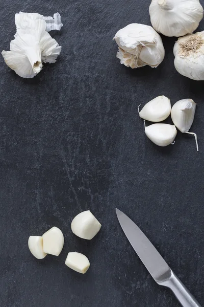 Garlic bulb and single cloves on slate — Stock Photo, Image