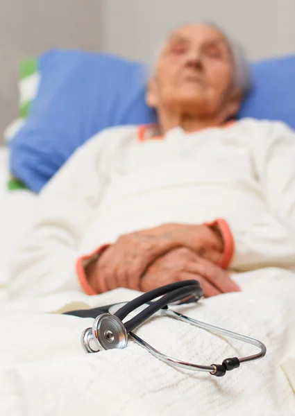 Frau liegt krank mit Stethoskop im Bett — Stockfoto