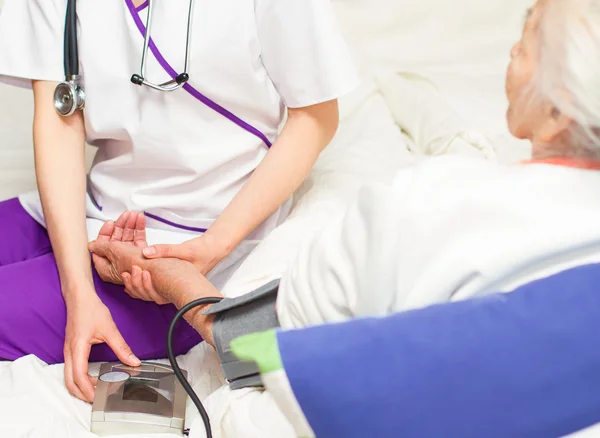 Tomar prssure sangue para um velho paciente lyin na cama — Fotografia de Stock