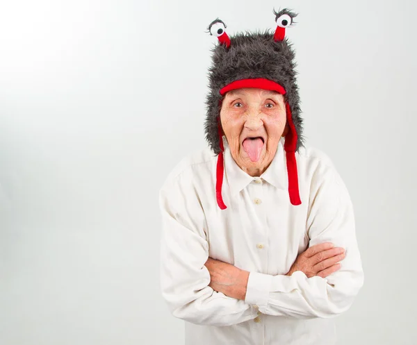 Grandma in funny hat showing her tongue — Stock Photo, Image