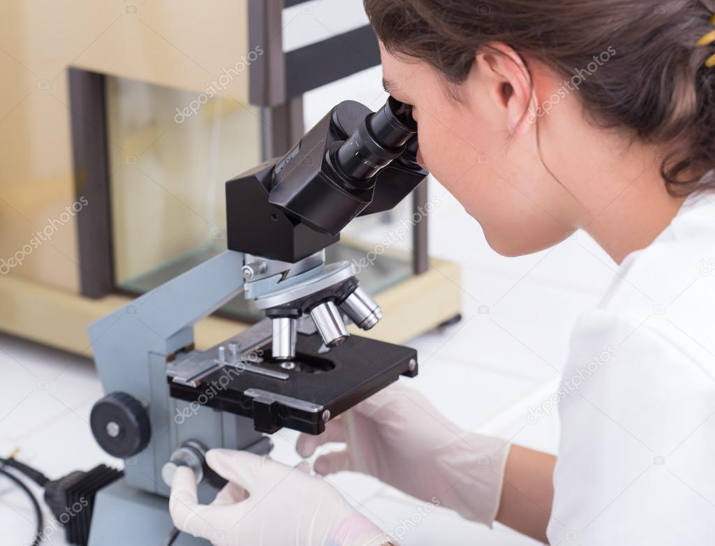 female student looking into the microscope