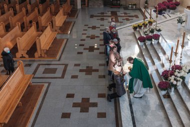 LUBIN, POLAND 19 Kasım 2020. Covid-19 Coronavirus salgını sırasında kilisedeki kutsal ayin. Rahip mübarek ekmeği sadıklara verir.