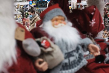 WROClaw, POLAND - 27 Kasım 2020. Süpermarkette yüz maskesi takan ve ön tarafta Noel süsü takan kadın. Koronavirüs salgını nedeniyle Covit-19 'da insanlar yüz maskesi takıyor..