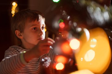 Noel ağacı süsleyen 8 yaşındaki bir çocuğun portresi.