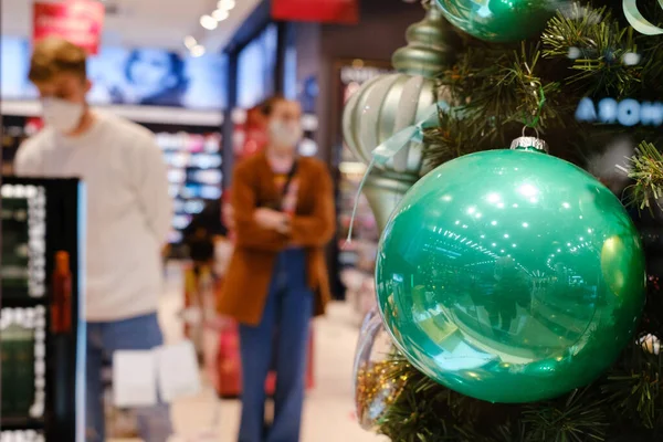 Christmas glass ball in the shop and people with face mask in the background.