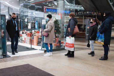 LUBIN, POLAND - 17 Aralık 2020. Güvenlik görevlisi ve maskeli adamlar Wroclavia 'daki mağazanın önünde kuyruğa girdiler. Covid-19 salgını nedeniyle dükkanda sınırlı sayıda insan var..