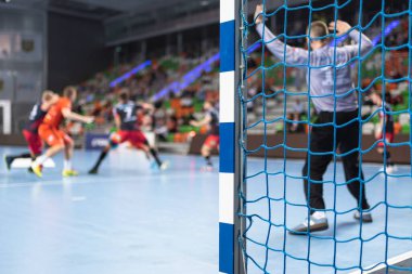 Hentbol kale direğinin ayrıntıları ve arka planda hentbol maçı.