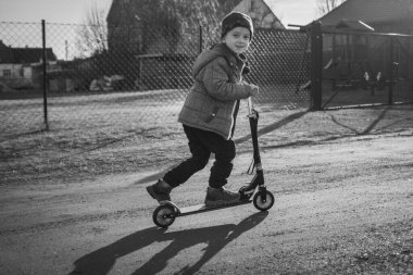 5 yaşında bir çocuk mobilete biniyor. Köy manzarası.
