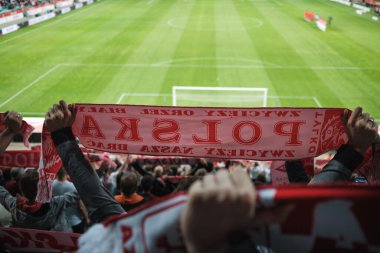 Bir futbol maçı sırasında bir taraftar tarafından tutulan Polonya (Lehçe) sözcüğüne sahip beyaz ve kırmızı bir eşarp.