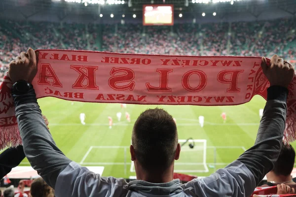 A white and red scarf with the word Poland (in Polish) held by a fan during a football match.