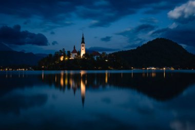 Kraliçe Mary 'nin çarpıcı Hac Kilisesi, Slovenya' nın Bled gölündeki küçük bir adada, mavi saatte dinleniyor..