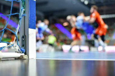 Hentbol kale direğinin ayrıntıları ve arka planda hentbol maçı.