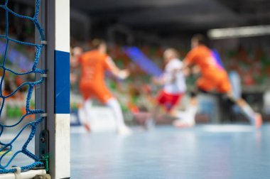 Hentbol kale direğinin ayrıntıları ve arka planda hentbol maçı.