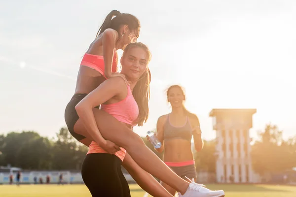 Glad ung kvinna piggybacking hennes vän — Stockfoto