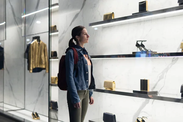 Kvinna står vid ett boutiquefönster och tittar på skor. — Stockfoto
