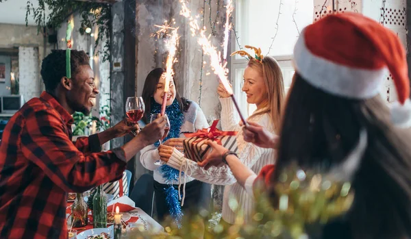 Grupo de pessoas que celebram o Natal ou a véspera de Ano Novo. Amigos brindam com bebidas e jantam juntos — Fotografia de Stock