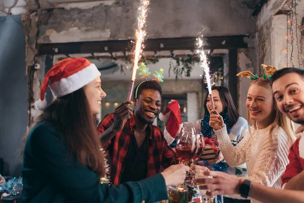 Amigos multi-étnicos a brindar vinho. Homens e mulheres jovens a dar uma festa. Natal, Ano Novo — Fotografia de Stock