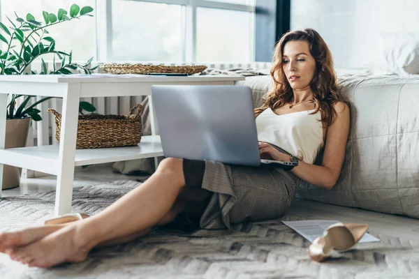 Porträtt av ung kvinna liggande på golvet med laptop — Stockfoto