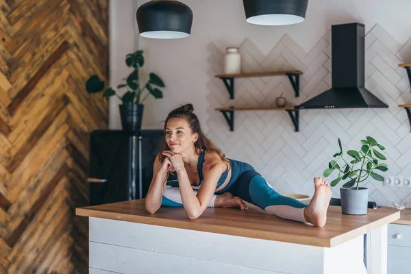 Mujer atlética flexible sentada en una mesa en casa — Foto de Stock