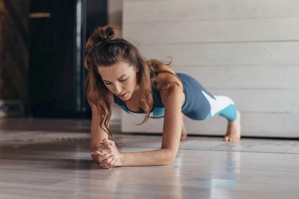 Passform kvinna gör planka motion, träning hemma — Stockfoto