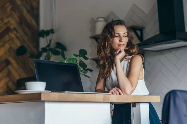 Porträtt av ung kvinna sitter vid bordet med laptop hemma. — Stockfoto