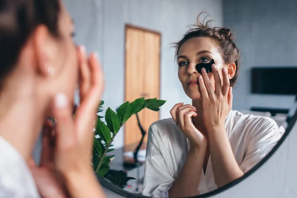 Mujer joven cuida su piel facial en casa — Foto de Stock