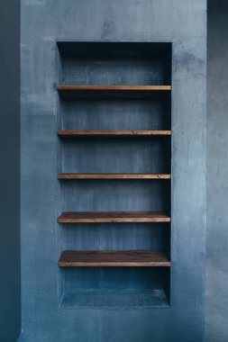 Ev içinde raflar var. Doğal malzemeler beton ve ahşap.