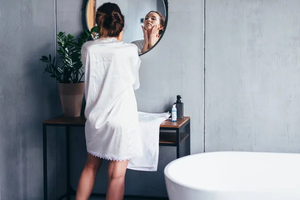 Жінка миє перед дзеркалом, наносить піну на обличчя — стокове фото
