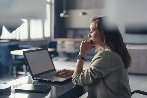 Affärskvinna i kostym arbetar med en bärbar dator vid sitt skrivbord på sitt hemkontor — Stockfoto