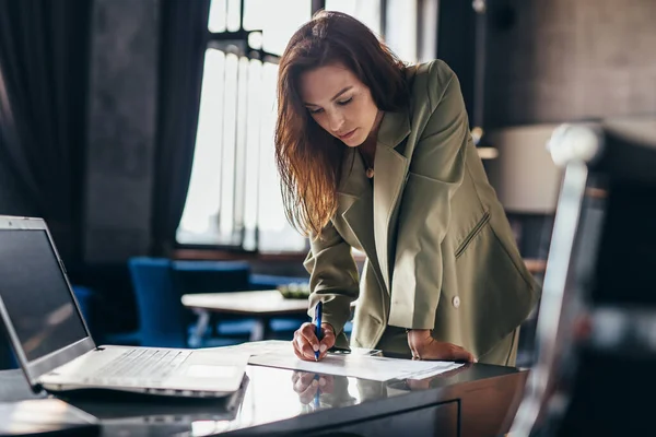 Femme entrepreneur se tient debout et écrit appuyé sur le bureau — Photo