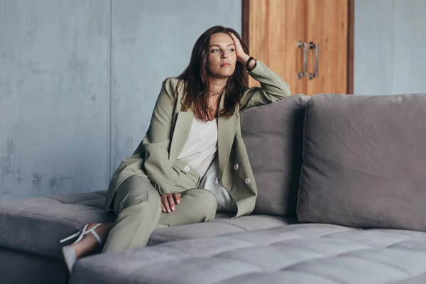 Frau im Anzug sitzt nachdenklich auf der Couch — Stockfoto