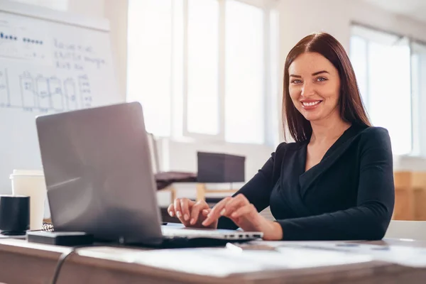 Empresária senta-se com seu laptop em seu local de trabalho — Fotografia de Stock